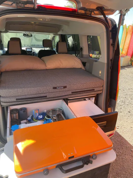 Compact rv rental camper setup features a comfy bed, pull-out kitchen, fridge, and portable stove. Ready for adventure!. Ford Transit Connect Wagon 2022