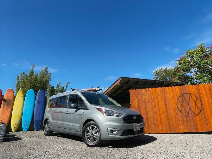 Gray Ford Transit Connect van, likely an rv rental, with surfboards & blue sky. Perfect for Hawaii adventures!. Ford Transit Connect Wagon 2022