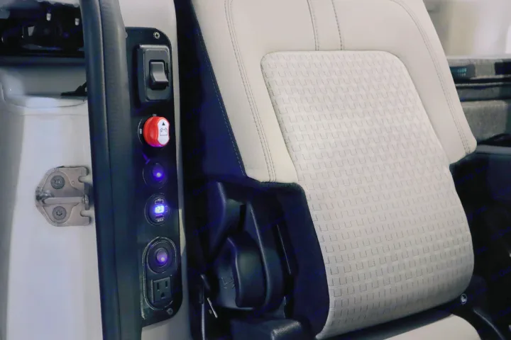RV rental power hub: Custom panel with AC outlet, USB ports, and battery monitor next to a comfortable seat.. Ford Transit Connect Wagon 2022