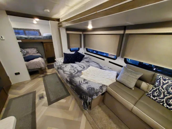 Modern RV rental interior with bunk beds, a main bed, and sofa, showcasing ample living and sleeping space.. Forest River Salem 2022