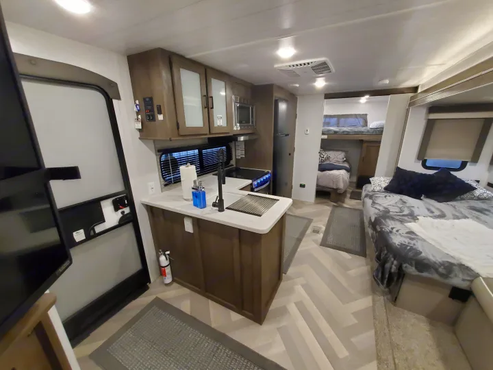 Spacious, modern RV rental interior featuring a full kitchen, comfortable main bed, and bunk beds for family adventures.. Forest River Salem 2022
