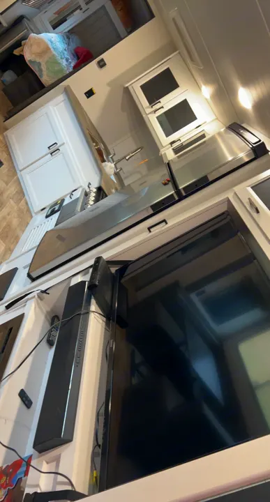 Inside an RV rental: a compact kitchen with a microwave oven. A large TV and soundbar are mounted below the counter for entertainment.. Keystone RV Hideout 2022