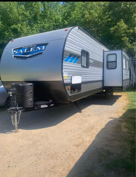 This grey and blue Forest River Salem travel trailer is an excellent rv rental for your outdoor adventures, parked on gravel.. Forest River Salem 2021