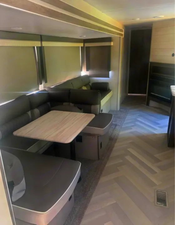 Modern RV rental interior: spacious dinette, compact kitchen, and light wood floors in a herringbone pattern.. Forest River Salem 2021