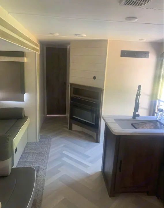 Inside a modern rv rental: kitchen island, cozy fireplace, comfy seating, and sleek herringbone flooring.. Forest River Salem 2021