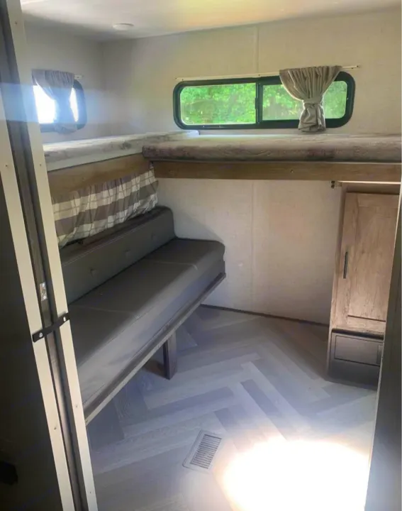 RV rental interior: two stacked bunks above a sofa, light wood-look floor, and sunny windows offering a view outside.. Forest River Salem 2021