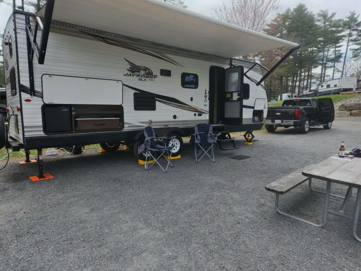 RV rental: a white Jayco travel trailer set up at a gravel campsite with awning extended, chairs, and a picnic table.. Jayco Jay Flight SLX 2019