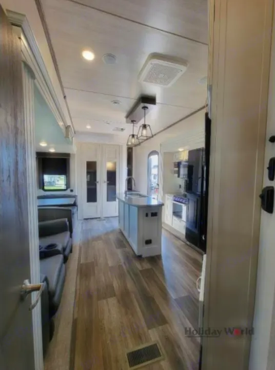 Modern RV rental interior with bright kitchen island, full appliances, and comfortable living area.. Keystone Cougar 2023
