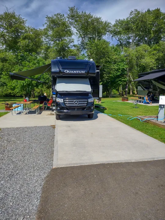 This black Thor Quantum RV rental is ready for camping, parked at a scenic site with an extended awning & outdoor setup.. Thor Quantum 2021