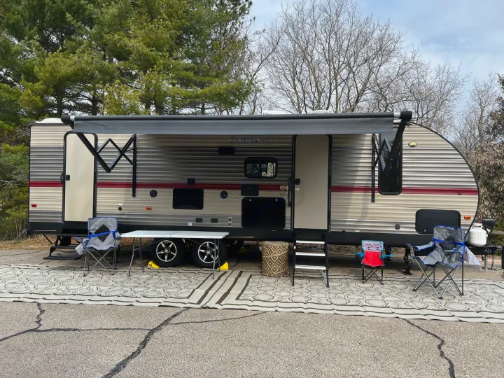 Travel trailer RV rental campsite setup with extended awning, outdoor mat, and chairs. Enjoy the great outdoors!. Forest River Cherokee 2019