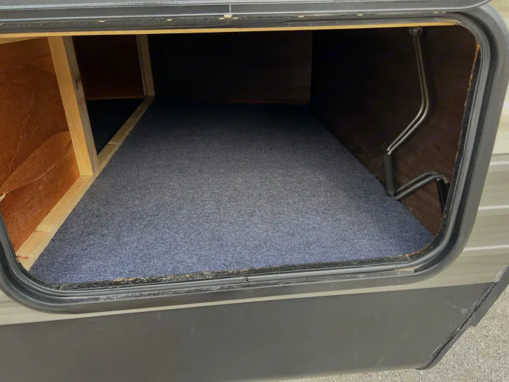 Empty, clean RV rental storage bay. Features carpeted floor, wood-paneled interior, ready for organized travel.. Forest River Cherokee 2019