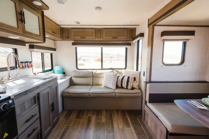 Bright RV rental interior with a spacious kitchen, comfortable sofa, and dining booth. Ideal for travel.. Gulf Stream Ameri-Lite 2021