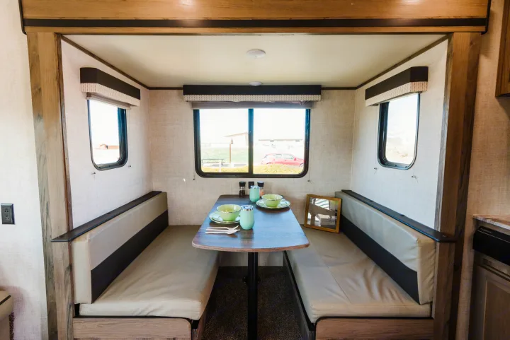 RV rental interior: Dinette with two benches, a set table, and windows offering views. Perfect for meals on the go.. Gulf Stream Ameri-Lite 2021