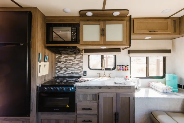 A spacious RV rental kitchen featuring a fridge, Greystone microwave/oven, sink, and sleek countertops.. Gulf Stream Ameri-Lite 2021