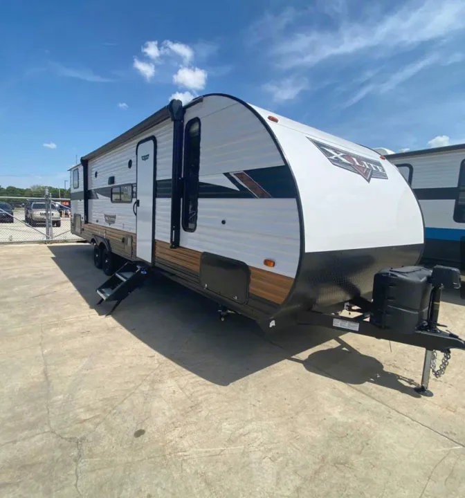 White & wood-toned travel trailer, perfect for an RV rental adventure, parked on a sunny concrete lot.. Forest River Forest River 2023
