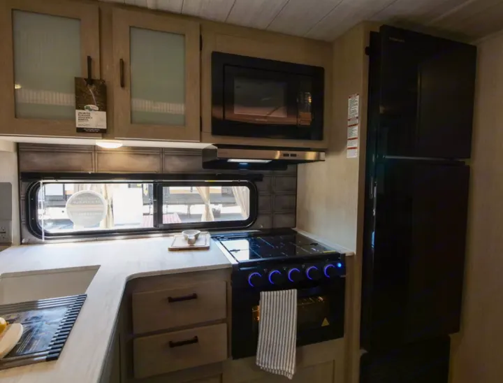 RV rental kitchen featuring a sink, microwave, stove with oven, and refrigerator.. Forest River Forest River 2023