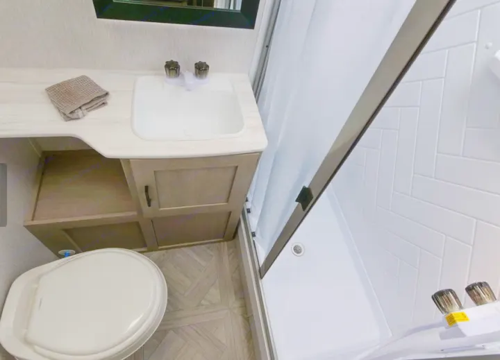 This compact RV rental bathroom features a white sink, toilet, and shower with tiled walls.. Forest River Forest River 2023