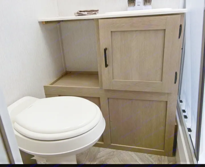 This RV rental bathroom features a compact toilet, modern wooden vanity with storage, and shower space.. Forest River Forest River 2023