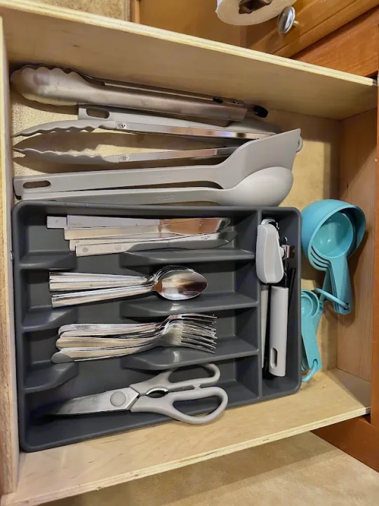 Efficient RV rental kitchen drawer: tongs, serving spoons, organized silverware, and measuring cups for easy cooking.. KZ Sportsmen 2009