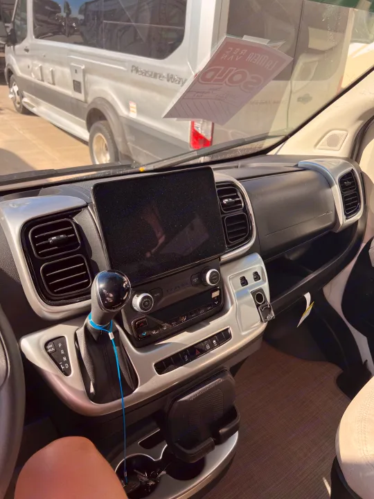 Dashboard of a Pleasure-Way RV, showing the screen and gear shifter. Ideal for an rv rental adventure.. Thor Tellaro 2023
