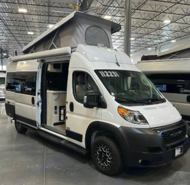 White Ram ProMaster pop-top camper van, ideal for RV rental. Side door open reveals compact, adventure-ready interior.. Thor Tellaro 2023