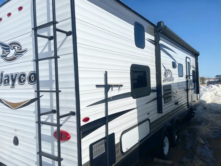 Explore this white Jayco Jay Flight travel trailer, perfect for an RV rental adventure. Visible ladder and awning.. Jayco Jay Flight SLX 2018