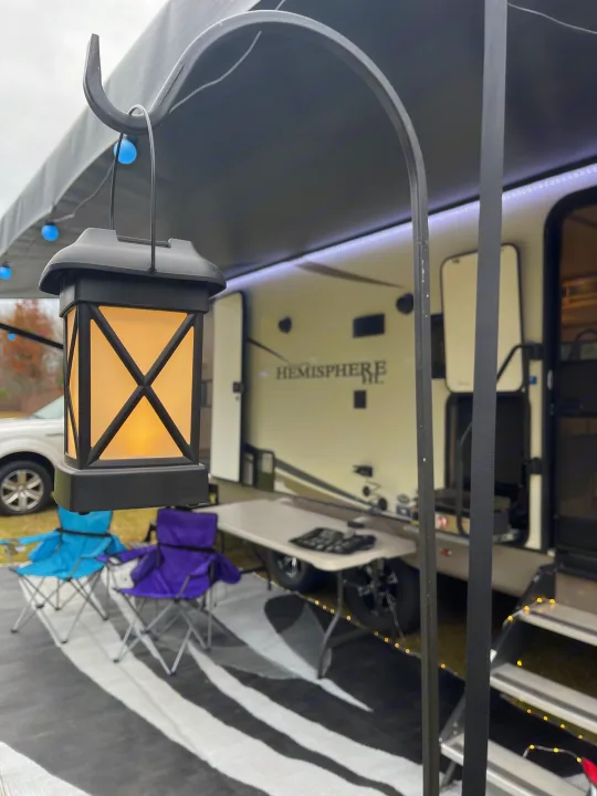 Relaxing RV rental outdoor patio with illuminated lantern, comfy chairs, and striped rug for your getaway.. Forest River Salem Hemisphere HL 2021