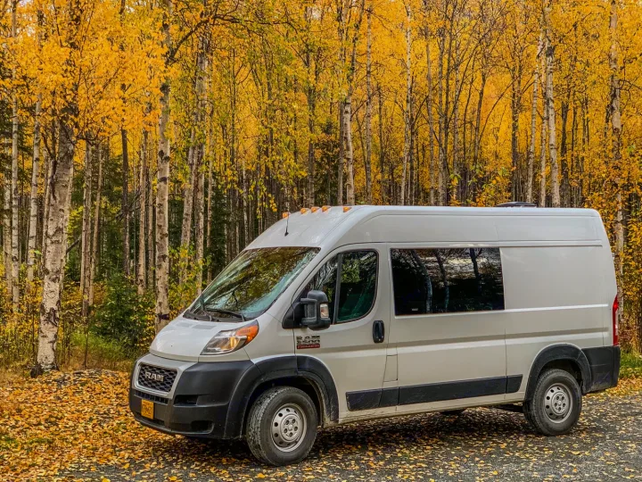 RV rental camper van in autumn. Parked among vibrant yellow birch trees and fallen leaves.. Dodge Ram 1500 2021