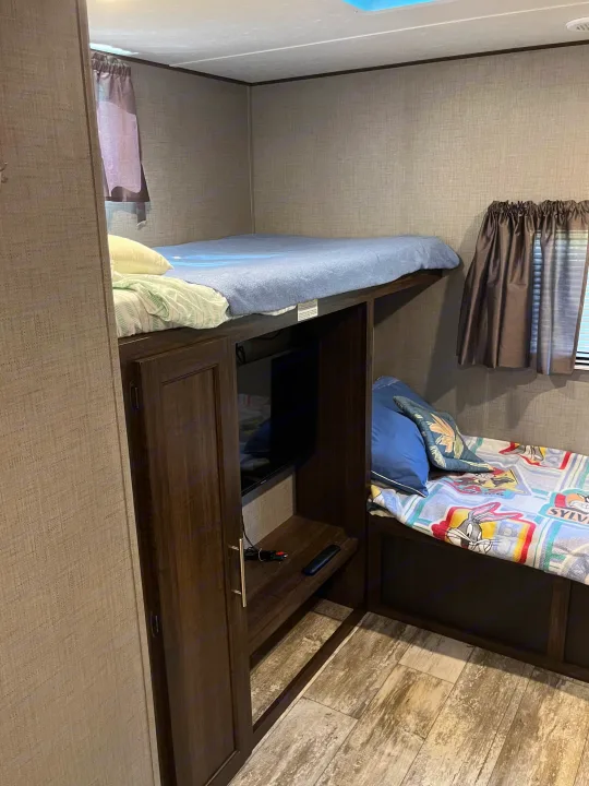 Cozy bunk beds and TV setup in an RV rental, perfect for family adventures.. Crossroads RV Zinger 2019