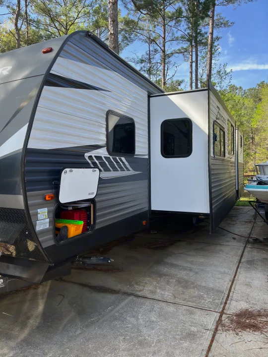 RV rental parked with an open door and storage hatch, ready for outdoor adventures on a concrete pad.. Crossroads RV Zinger 2019