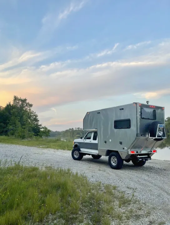 Custom truck camper/RV by a lake at sunset. Imagine your next rv rental adventure here!. Ford F250 1997