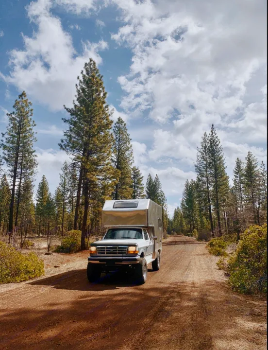 Exploring nature! This truck camper, ideal for RV rental, is ready for forest adventures on a remote dirt road.. Ford F250 1997