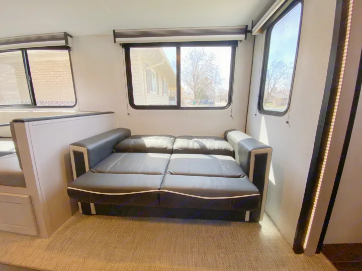 RV rental interior featuring a black leather sofa bed, dinette, and bright windows for a comfortable living space.. Heartland RVs Mallard 2022