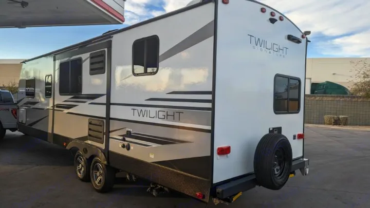 This white Twilight Signature travel trailer, perfect for an RV rental, is parked, showing its side and rear.. Twilight RVS Signature 2022