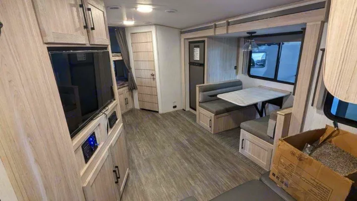 Modern RV rental interior: dinette, entertainment center, fridge, and bunk beds, showcasing a functional travel trailer layout.. Twilight RVS Signature 2022