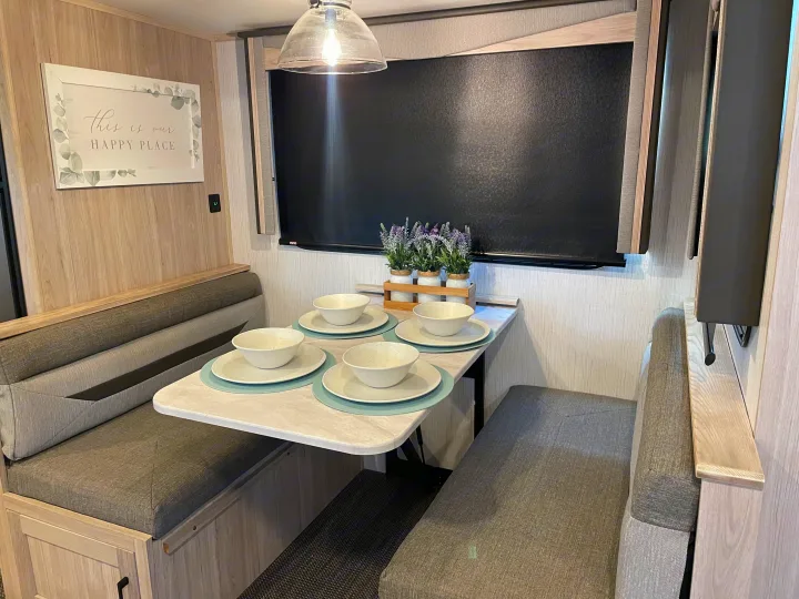 Comfortable RV rental dinette interior with modern design, ready for dining. Features a set table and cozy bench seating.. Twilight RVS Signature 2022