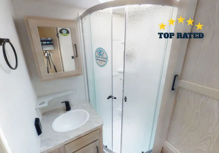 Top-rated RV rental bathroom features a light vanity, white sink, and curved glass shower.. Forest River Rockwood Roo 2021