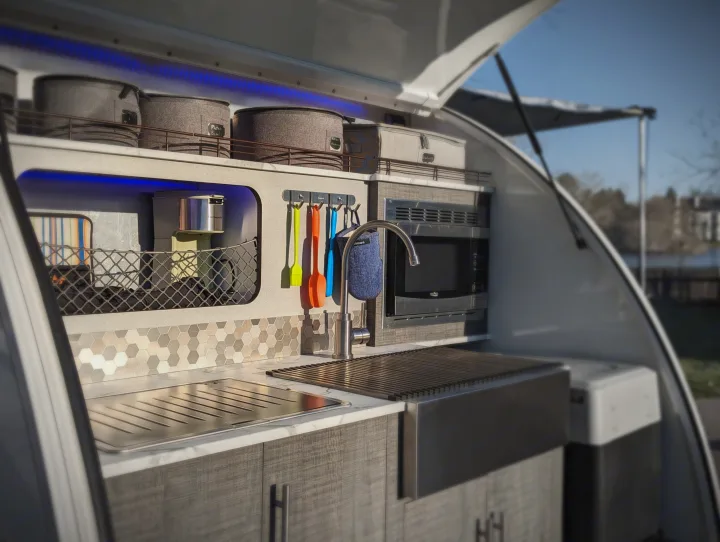 Sleek outdoor camper kitchen in an RV rental, showing a sink, microwave, and organized storage for camping trips.. InTech RV InTech RV Trailer 2021