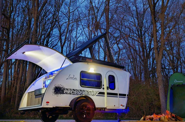 Enjoy the outdoors! This Luna Rover teardrop RV rental, fully lit, awaits adventure with a cozy campfire and tent at dusk.. InTech RV InTech RV Trailer 2021