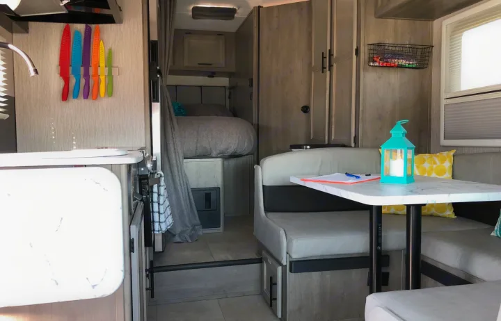 RV rental interior: kitchen with colorful knives, cozy bedroom, and dinette with turquoise lantern. Perfect compact living.. Forest River Coachmen Cross Trail XL 2022