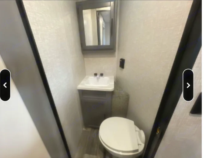 Compact RV rental bathroom with sink, mirror, and toilet, featuring light walls and wood-look flooring.. Crossroads RV Volante 2021