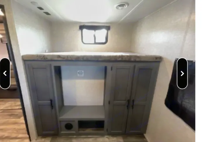 RV rental interior features a bunk bed above gray cabinets, offering storage and an entertainment space.. Crossroads RV Volante 2021