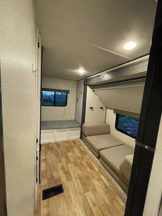 Inside an RV rental: Compact living area with a bench/bunk bed, modular seating, and wood-look floor.. Keystone RV Hideout 2022
