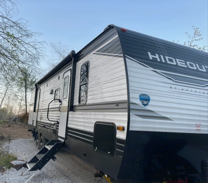 Experience a Hideout by Keystone travel trailer. This RV rental is parked with steps out, ready for your outdoor trip.. Keystone RV Hideout 2022