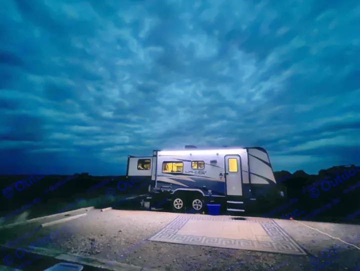 A modern RV rental lights up the dark campsite under a dramatic, cloudy night sky. Ready for outdoor adventure.. Starcraft Launch 2018