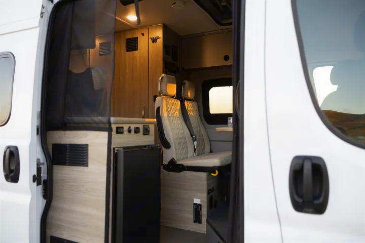 Explore your next RV rental: modern camper van interior with swivel seats, galley, and storage.. Winnebago Solis 2022