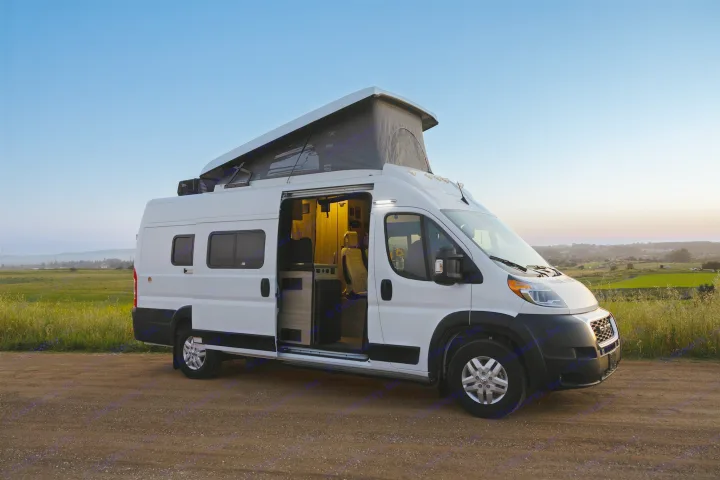 A white pop-top camper van with open door and lit interior on a dirt road at dusk. Perfect for your next rv rental journey.. Winnebago Solis 2022