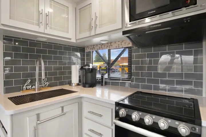 Tour this RV rental's sleek kitchen! It boasts a stove, microwave, Keurig, and chic grey tile backsplash.. Keystone RV Bullet Premier Ultra 2021
