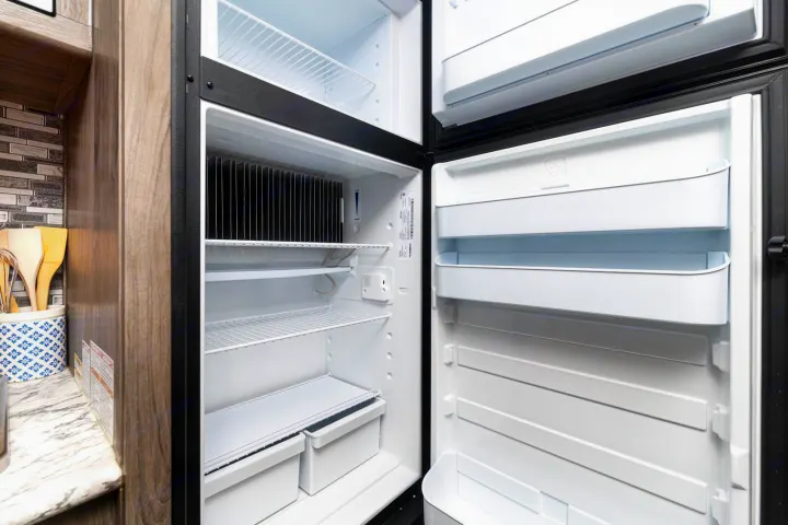 View inside a clean, empty RV rental refrigerator and freezer. Spacious interior with shelves and storage compartments.. Gulf Stream Ameri-Lite Super Lite 2022