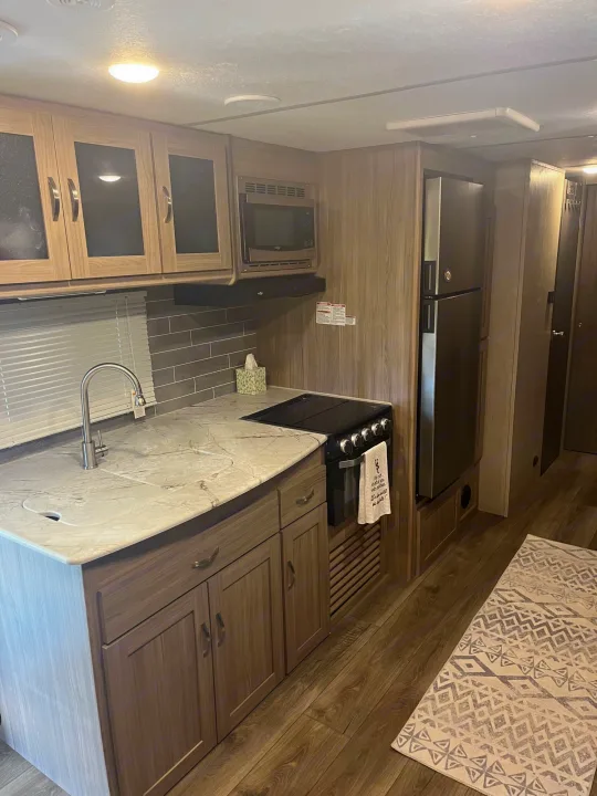 A bright and fully equipped RV rental kitchen, showcasing modern appliances like a fridge, microwave, stove, and sink.. Coachmen Freedom Express 2021